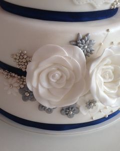 Svatební dort - modrá stuha, perličky a dvě bílé růže